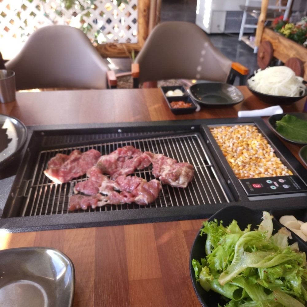 식당 테이블에 설치된 콘터치그릴 위에 생고기가 올려진 모습