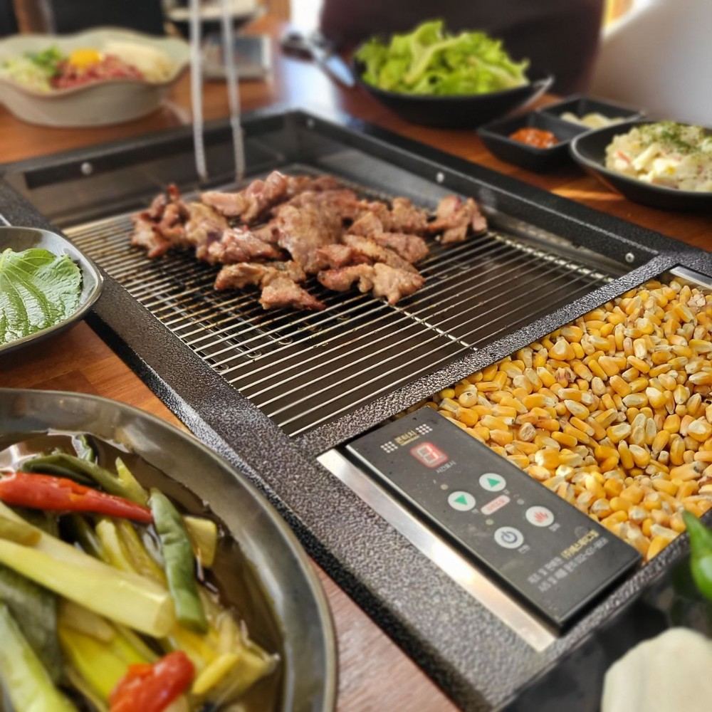 석쇠 위 양념 고기와 옆 칸의 옥수수 연료